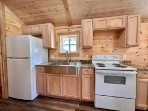 kitchen area with refrigerator, sink, stove etc., in cabin mobile home