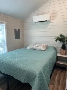 bed room with a mini split ac and queen size bed - full house park model manufacturer demo